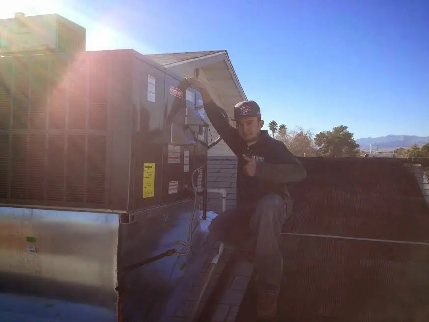 HVAC technician performing Boiler Repair on a rooftop unit in Broussard